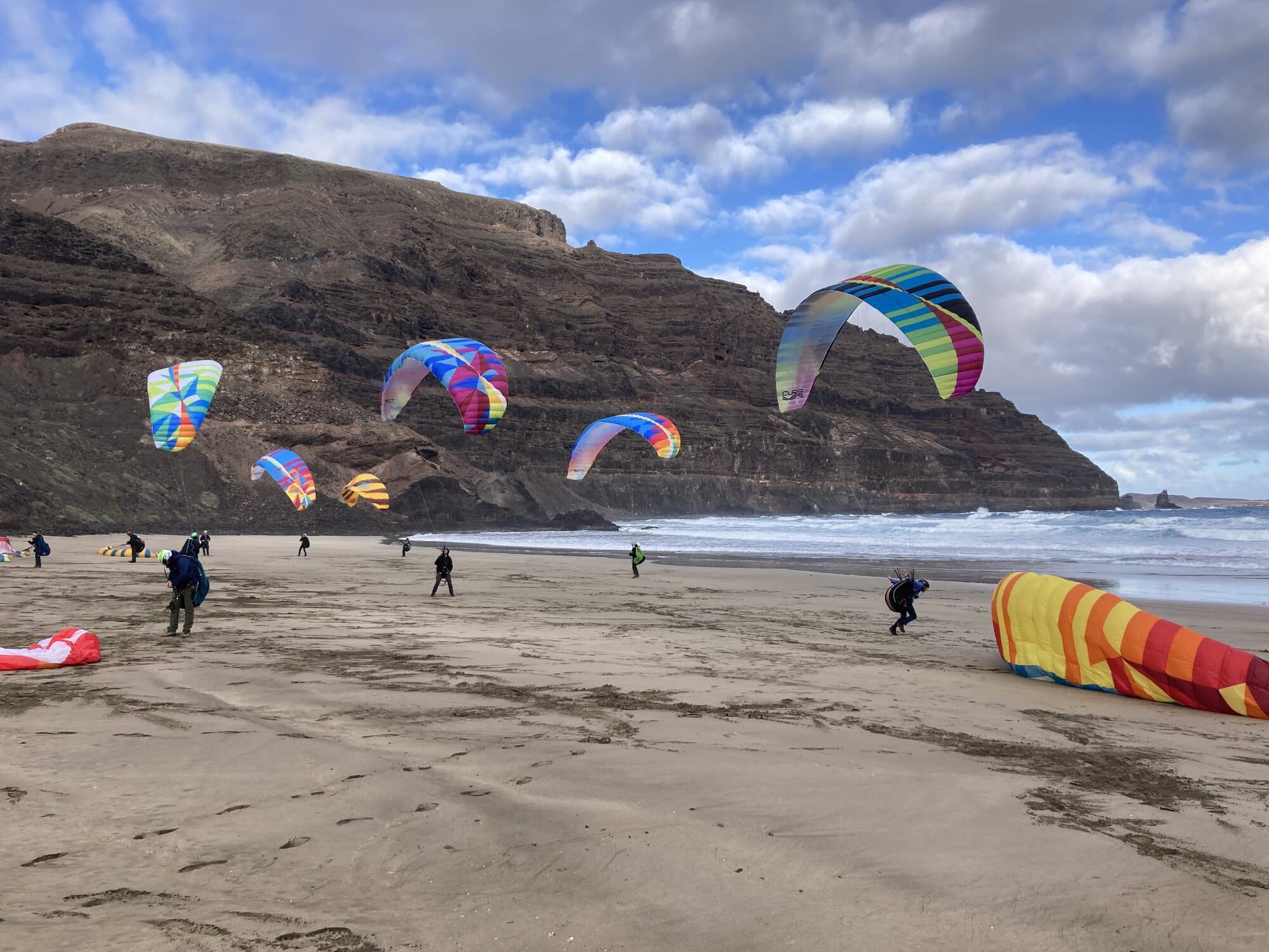 Paragliders ground handling on Famara beach in Lanzarote, under the cliffs